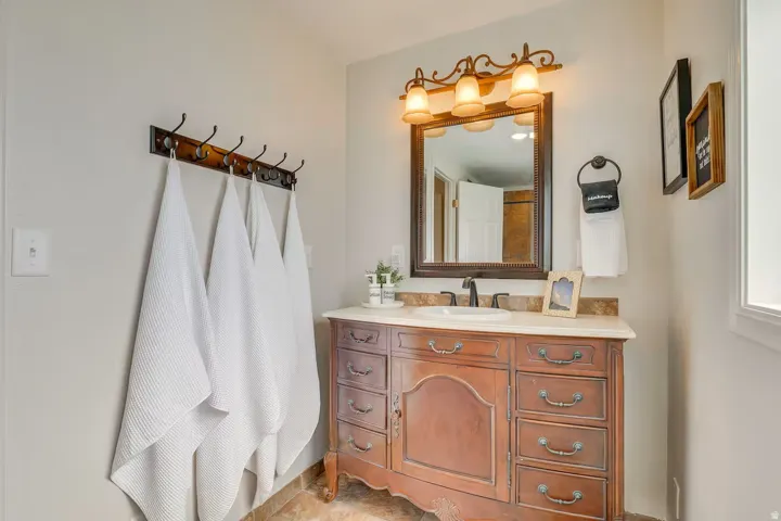 Wood-finish vanity with multiple storage drawers, single-basin sink, and a framed mirror