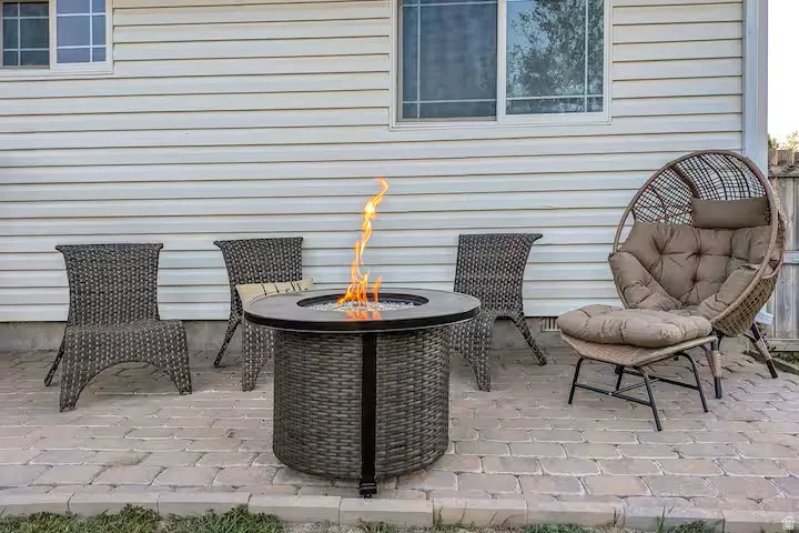Paved patio with a built-in fire pit, set against a backdrop of horizontal siding