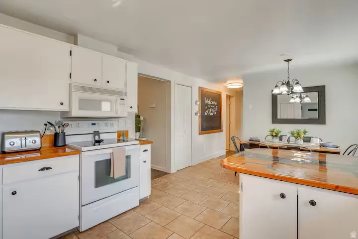 Kitchen featuring white cabinetry with dark hardware, a built-in microwave, and a white electric range