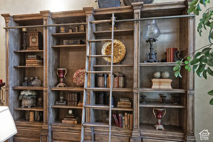 Built-in wood shelving units with a distressed finish, integrated rolling ladder, and a continuous metal rail