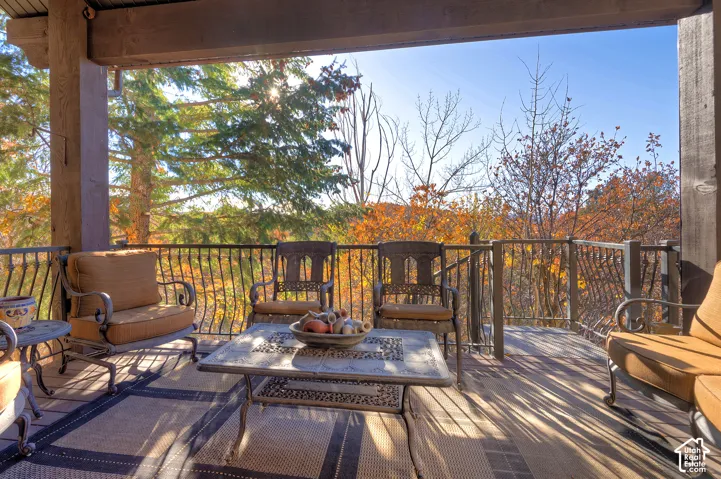 Covered outdoor deck with wood flooring, dark metal railings, and natural surroundings