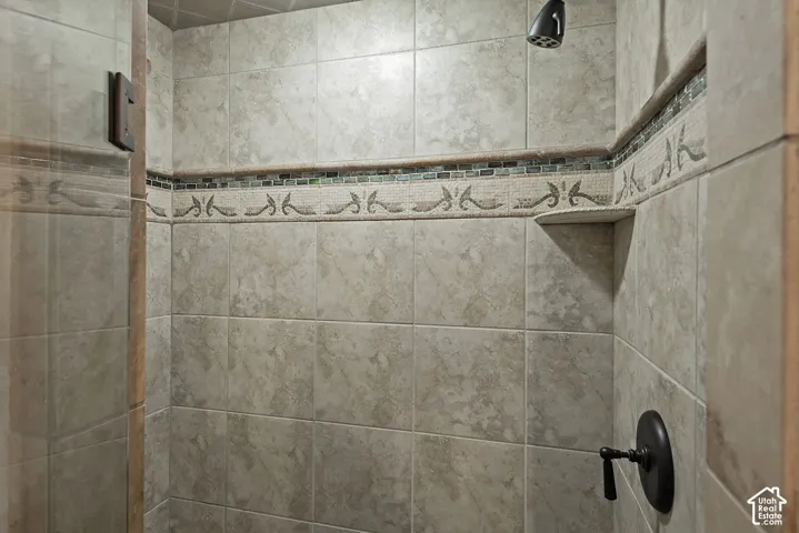 Tiled shower enclosure featuring decorative tile accents, built-in shelving, and a matte black shower head and control handle