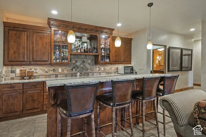 Custom cabinetry with glass-front display, granite countertops, and mosaic tile backsplash