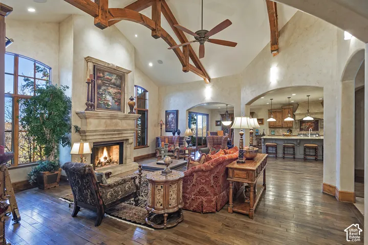 Wood-finish flooring throughout, a vaulted ceiling with exposed wood beams, and an impressive stone fireplace with a substantial mantel