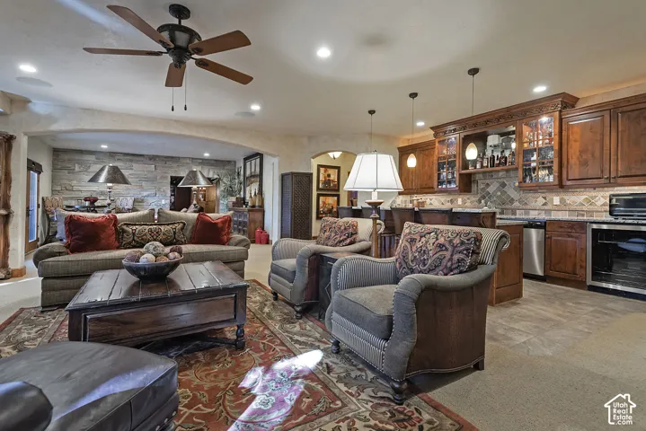 Recessed ceiling lighting, wood-finish ceiling fan, wood-finish cabinetry, stainless steel appliances, and stone backsplash