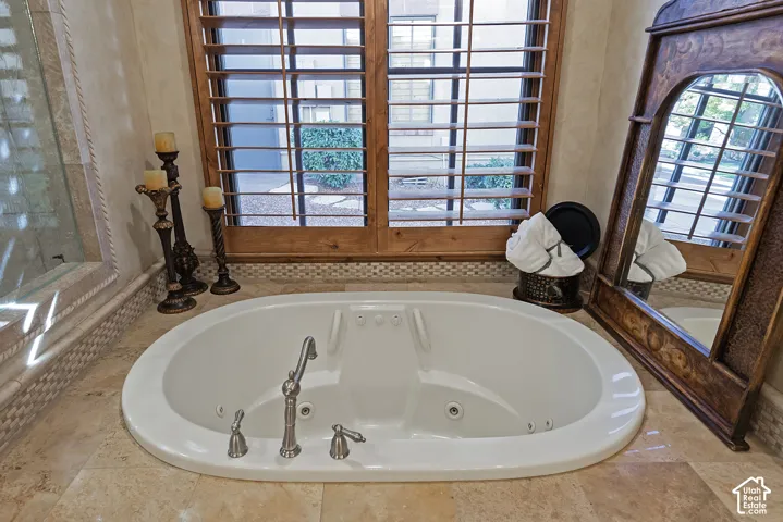 Built-in jetted tub with an integrated faucet, surrounded by tiled flooring and a wood-slatted window treatment