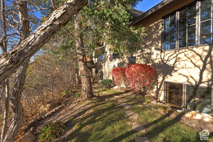 Exterior property showcasing multiple windows, a foundation with lower-level windows, mature trees, and established shrubbery