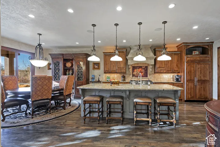 Kitchen with a large island featuring a stone countertop, wood cabinetry, and a built-in refrigerator