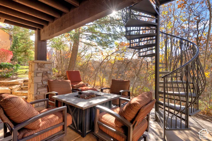 Covered patio with a stone-clad support column, open-beam ceiling, and spiral metal staircase