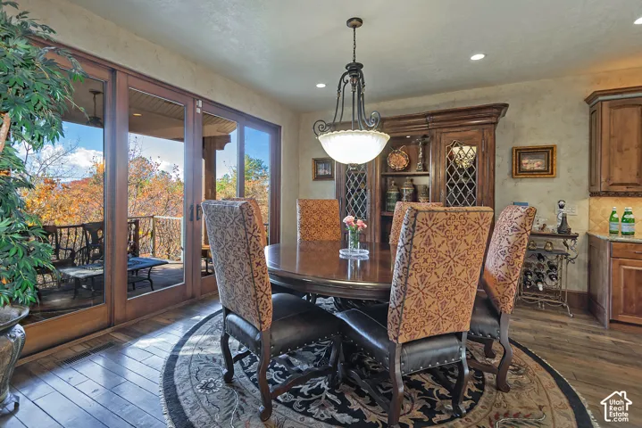 Hardwood flooring, wood-framed glass doors, built-in cabinetry with glass inserts, recessed lighting, and a decorative pendant light fixture