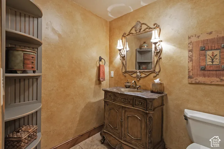 Ornate vanity with integrated sink, sconce lighting, decorative mirror, and textured wall finish