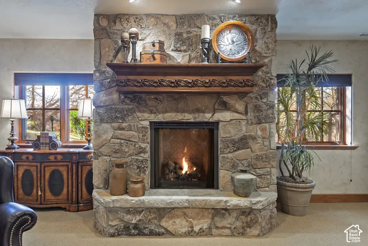 Stone-clad fireplace with a carved wood mantel, featuring a raised stone hearth and a built-in firebox