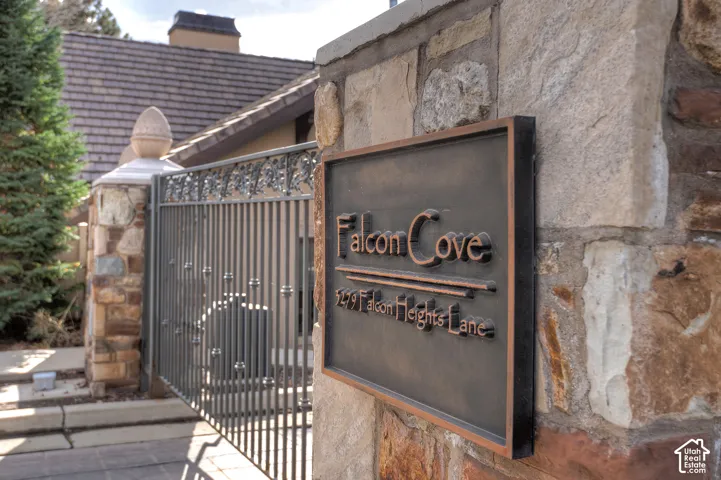 Stone column entrance with an ornate wrought iron gate, featuring a custom property sign and finial accents