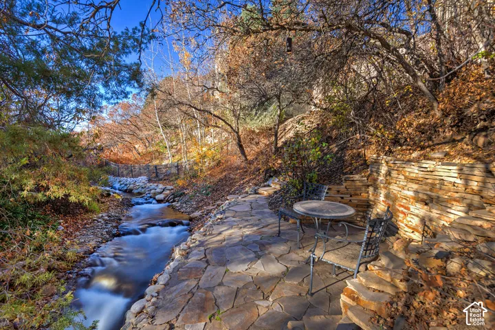 Stream-side flagstone patio featuring a natural rock wall and a tiered stone retaining wall