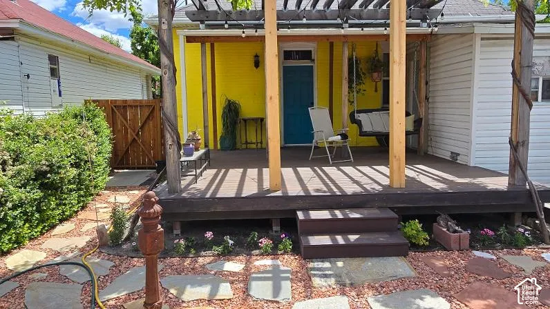 Wood deck with an overhead pergola, two-step wood entry, and stone pavers