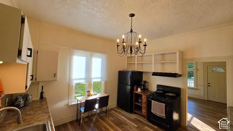 Kitchen featuring wood-finish flooring, white cabinetry with black hardware, and an ornate black chandelier