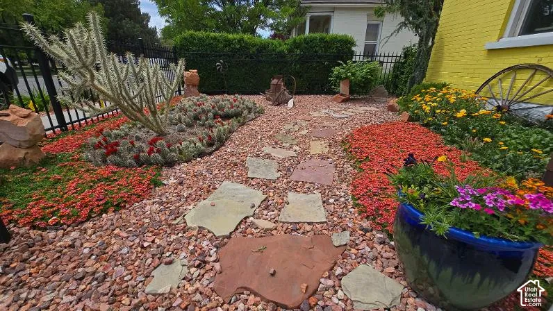 Rock garden with diverse plant selections, flagstone path, and metal fencing