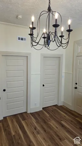 Wood-finish flooring with a multi-paneled door, complete with a six-light chandelier and wall paneling