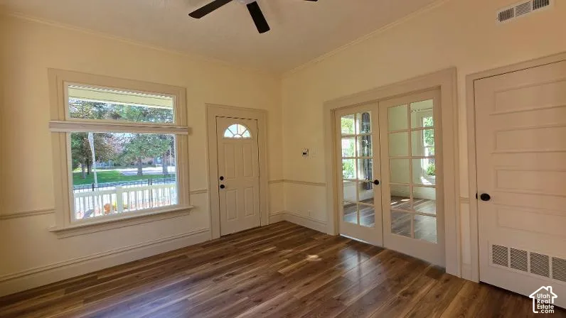 Wood-finish flooring with neutral wall tones, crown molding, and wainscoting