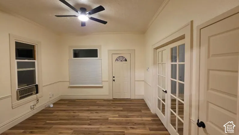 Wood-finish flooring, ceiling fan with integrated lighting, paneled wainscoting, French doors, and substantial window trim