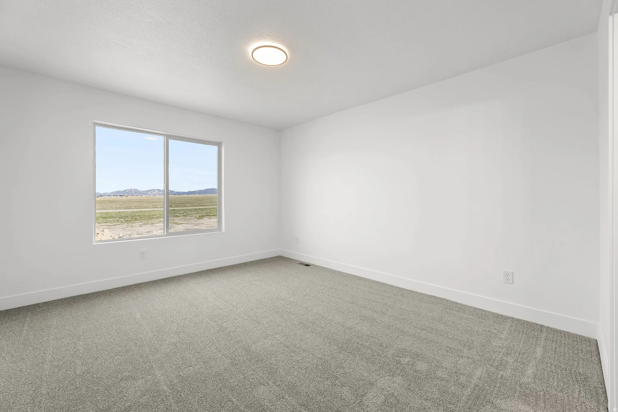 Recessed lighting, light-toned carpeting, and a large window providing expansive scenery