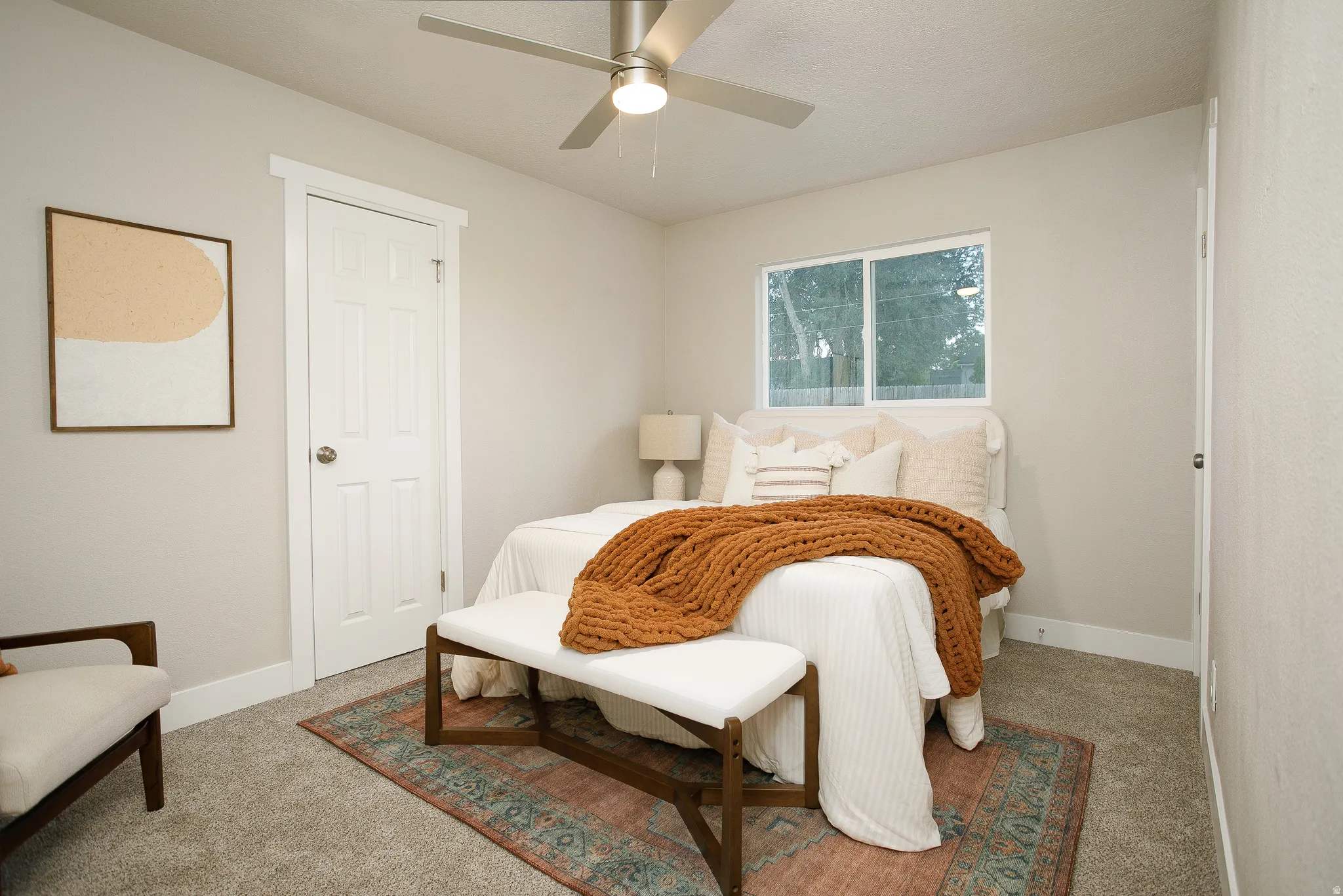 Neutral-toned walls, plush carpet flooring, a ceiling fan with integrated lighting, and a white-framed window