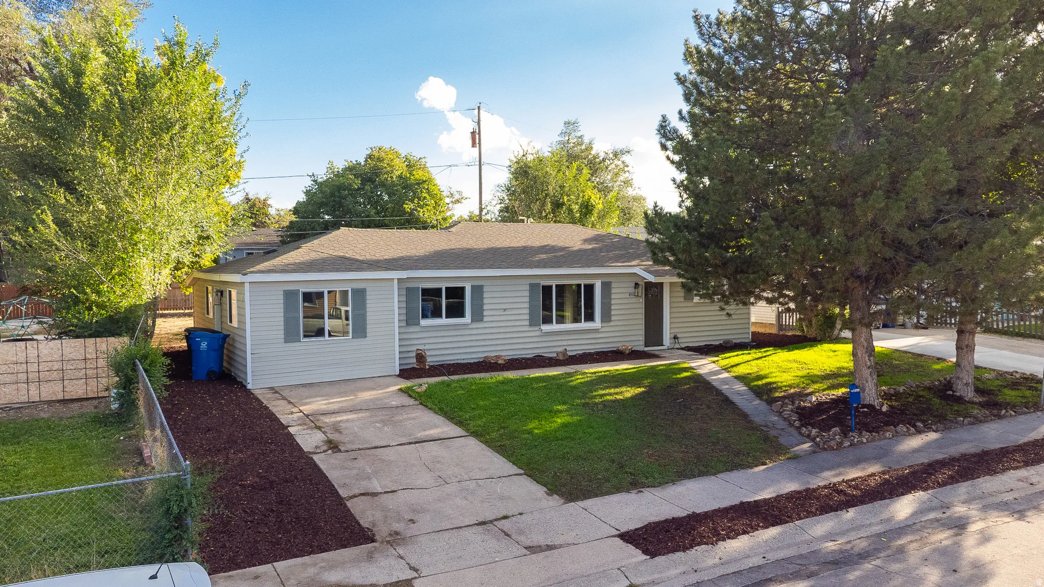Single-story residence featuring light-colored siding, a paved driveway, and a shingled roof