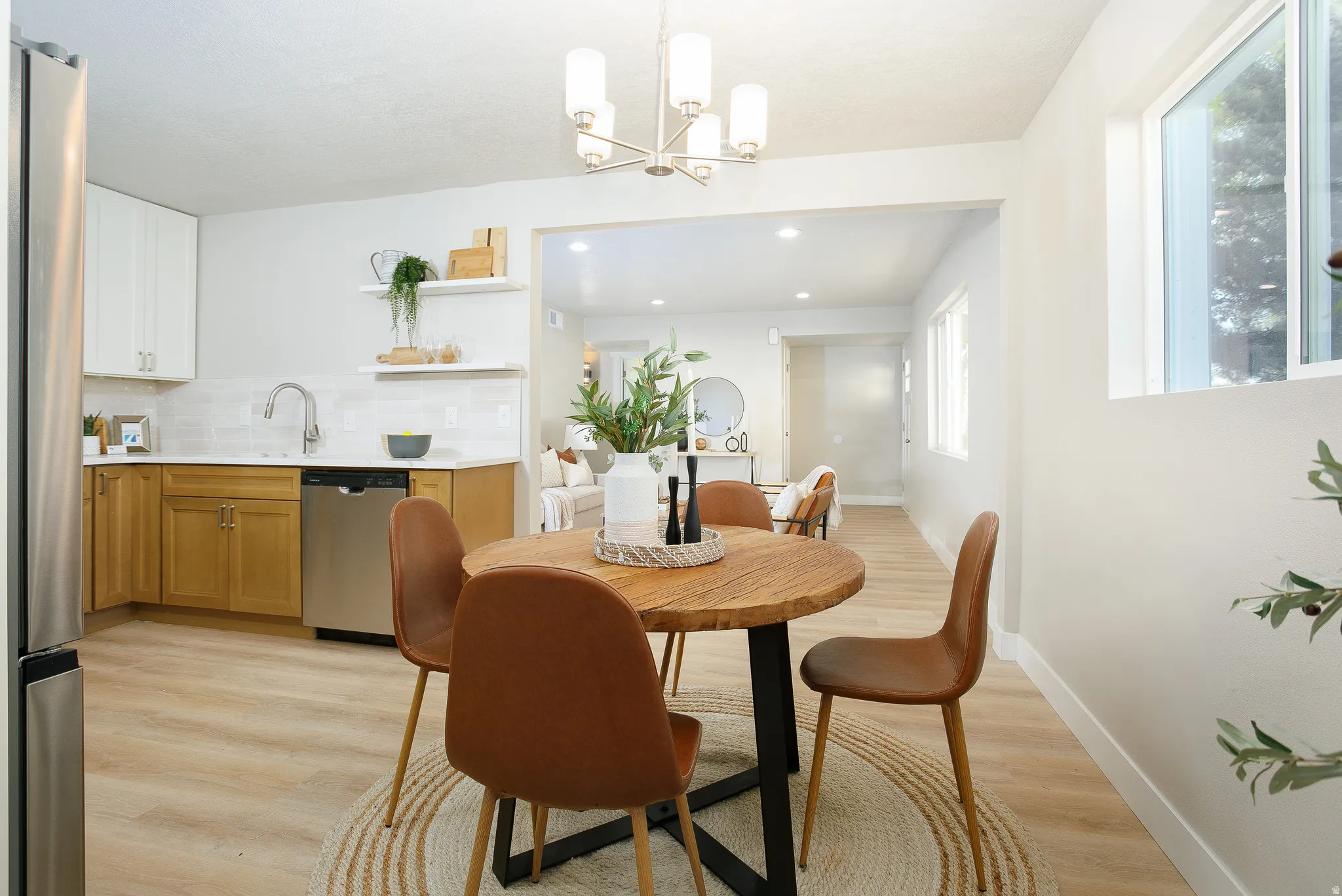 Kitchen and dining area featuring two-tone cabinetry, stainless steel appliances, and wood-finish flooring