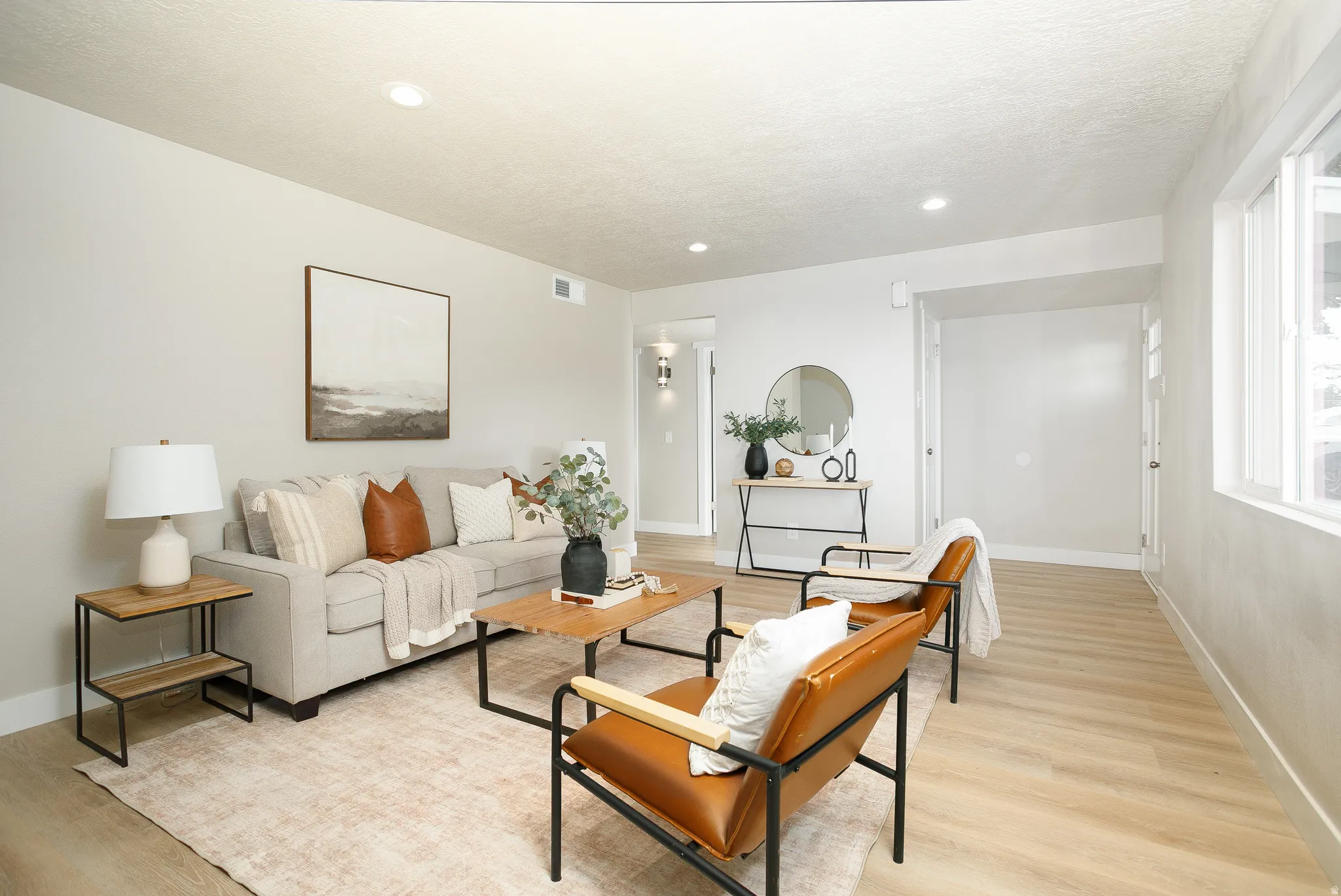 Recessed lighting, light wood-finish flooring, white trim, and a window providing natural illumination
