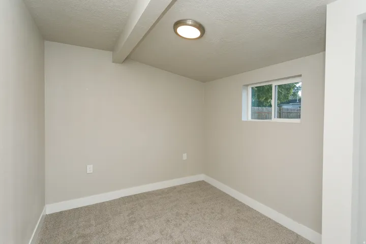 Carpeted flooring, recessed ceiling beam, flush-mount ceiling light, white trim, and a functional window