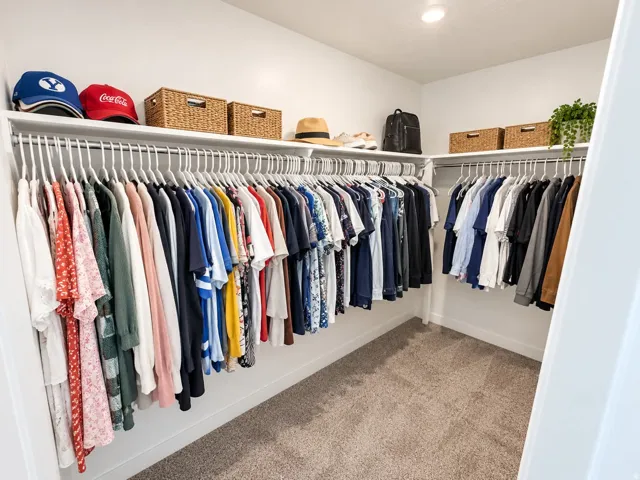 Corner closet with white walls, recessed lighting, carpet flooring, and integrated shelving and hanging rods