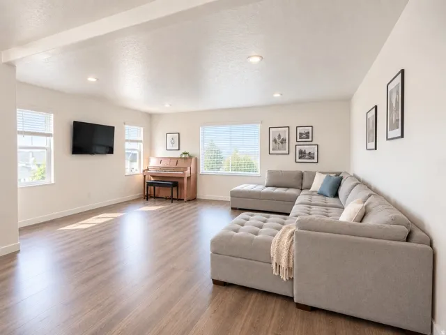 Recessed lighting illuminates the spacious room with wood-finish flooring and multiple windows