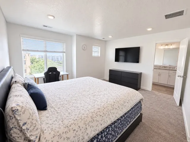 Carpeted room with recessed lighting and a large window with blinds