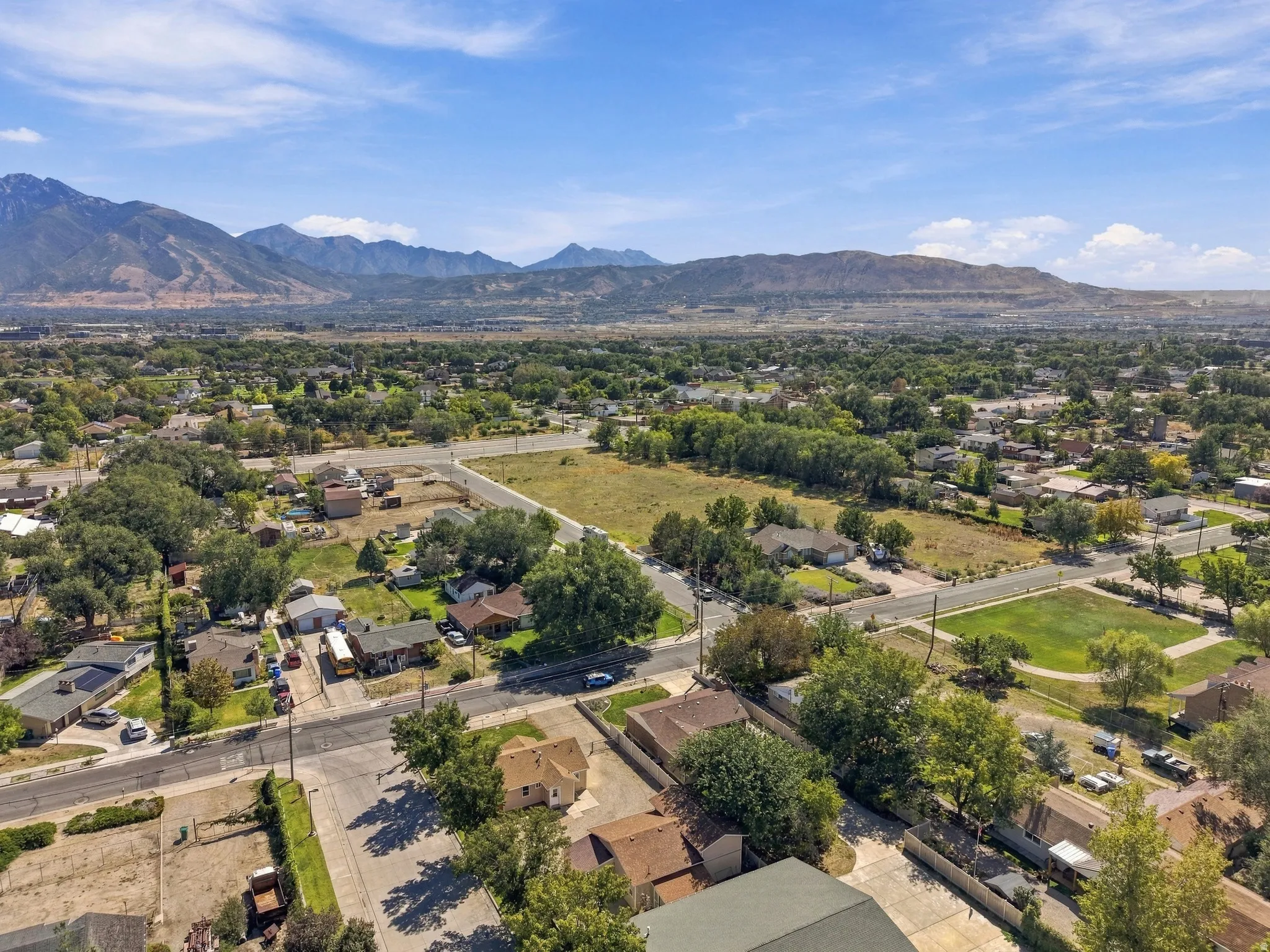 Expansive aerial view of a residential area with mature trees, surrounded by distant mountains