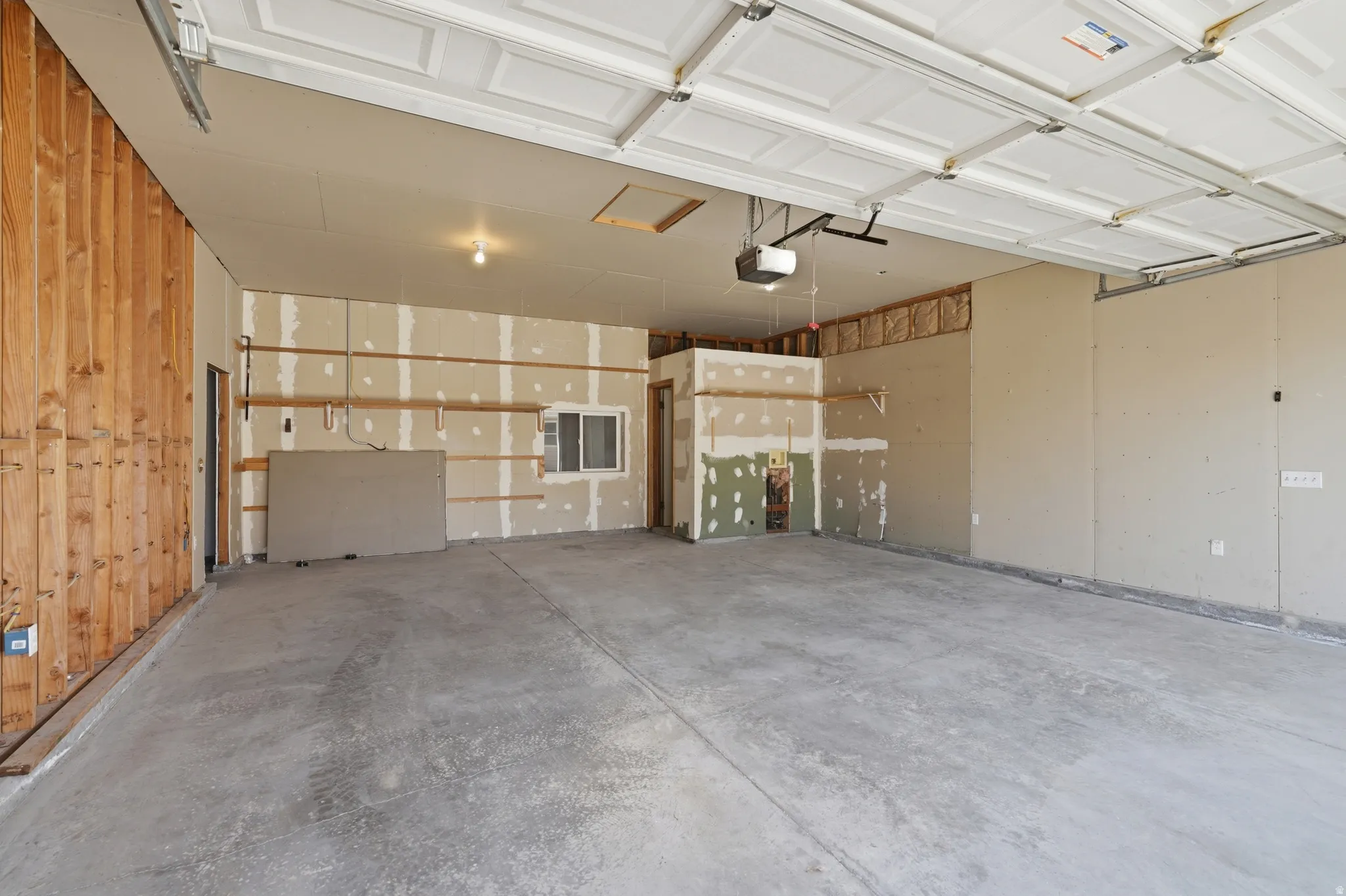 Spacious garage featuring a concrete floor, overhead lighting, and built-in garage door opener