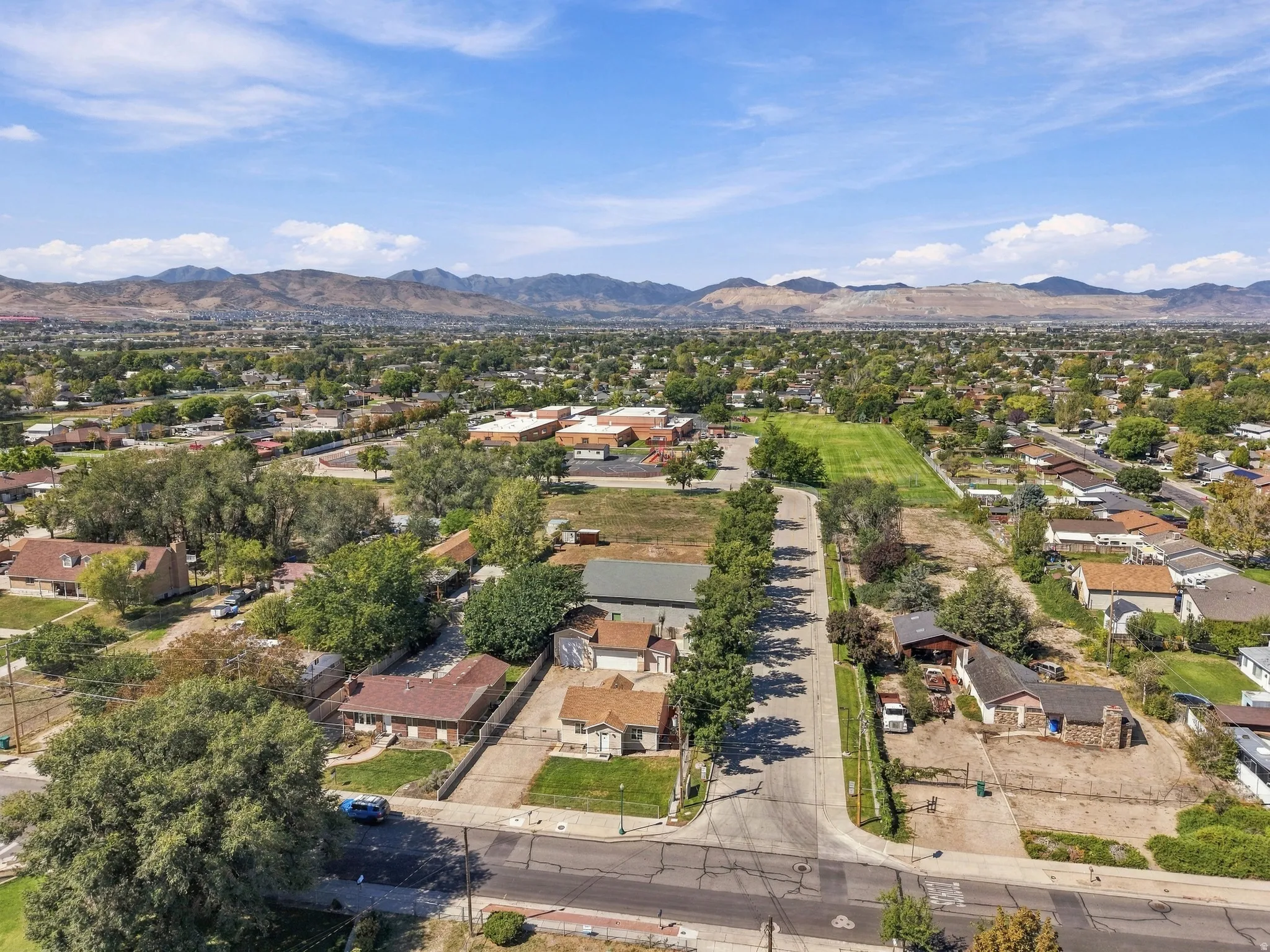 Expansive residential setting with mature trees, established properties, and distant mountain ranges