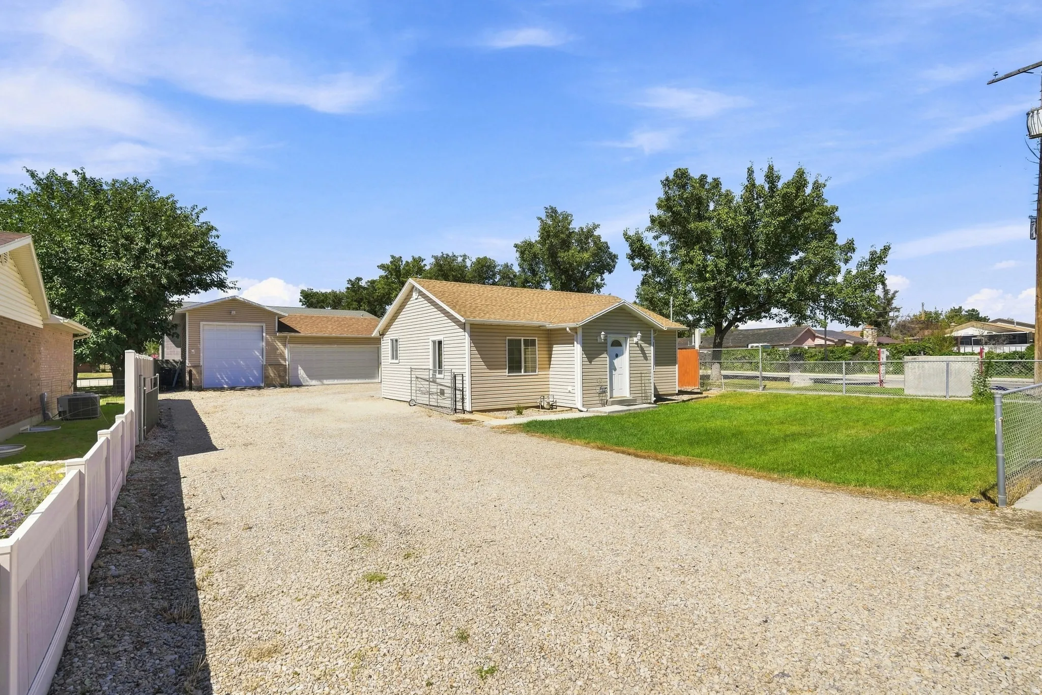 Gravel driveway, two detached garages, fenced yard, and a separate outbuilding
