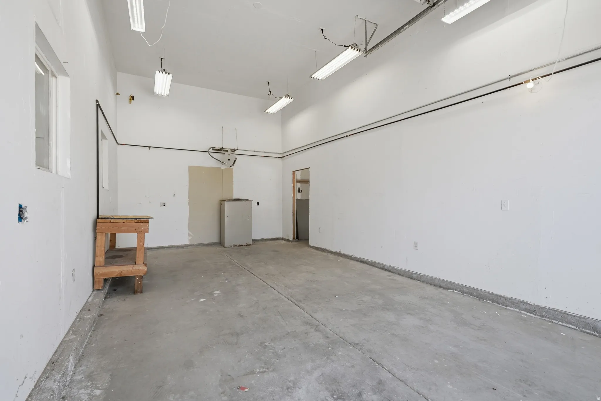 Concrete flooring, white painted walls, and ample overhead lighting