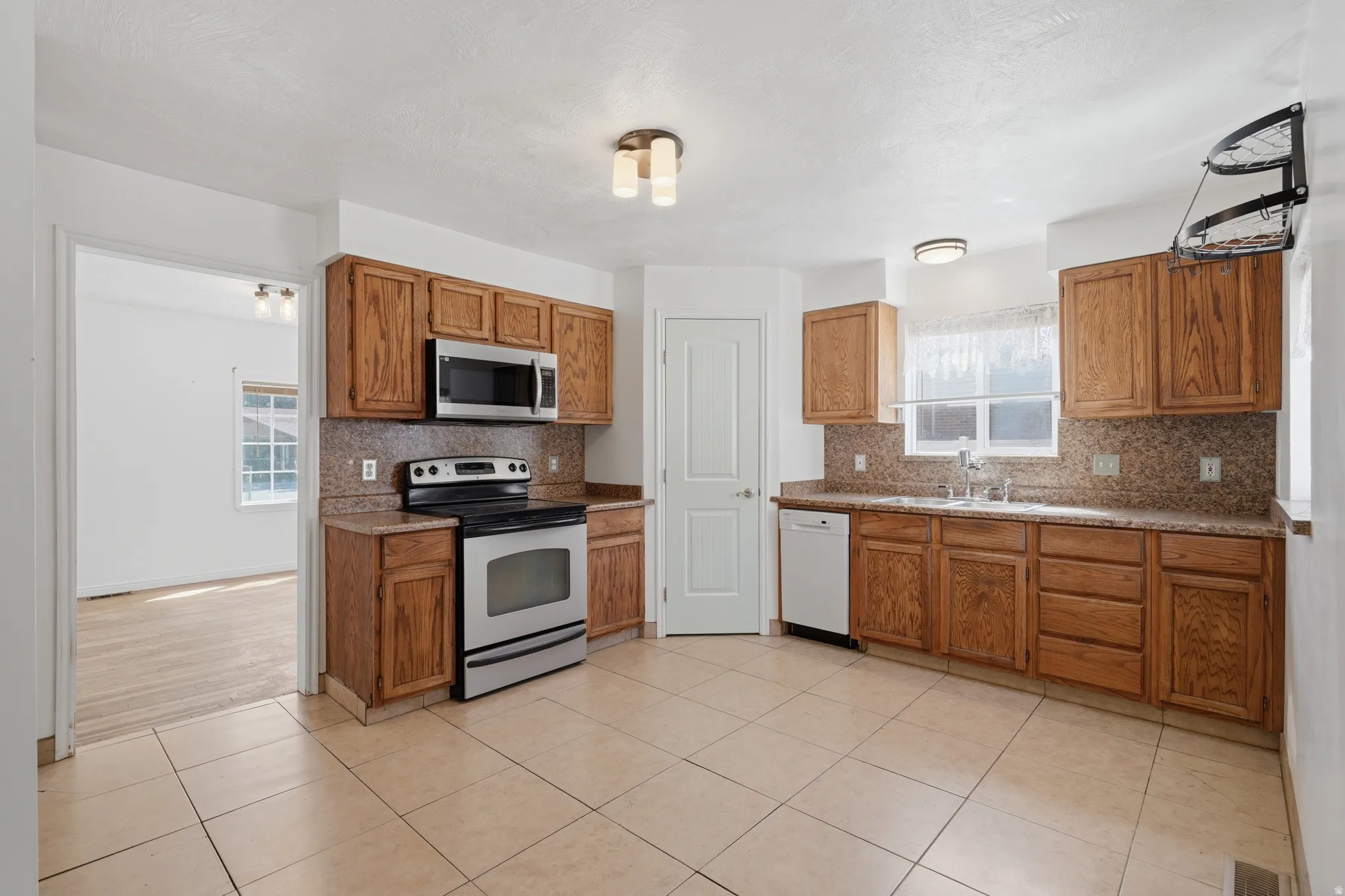 Kitchen featuring wood cabinetry, stainless steel appliances, granite-look countertops, and tile flooring