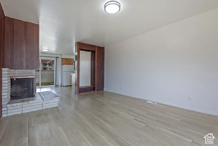 Wood-finish flooring, brick-faced fireplace, wood paneling, built-in cabinetry, and sliding glass door