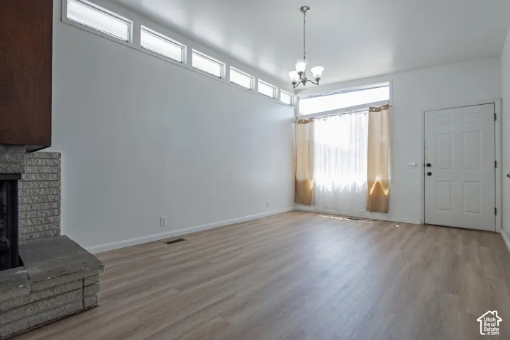 Wood-finish flooring, white walls, stone-clad fireplace with hearth, multiple transom windows, and an overhead light fixture