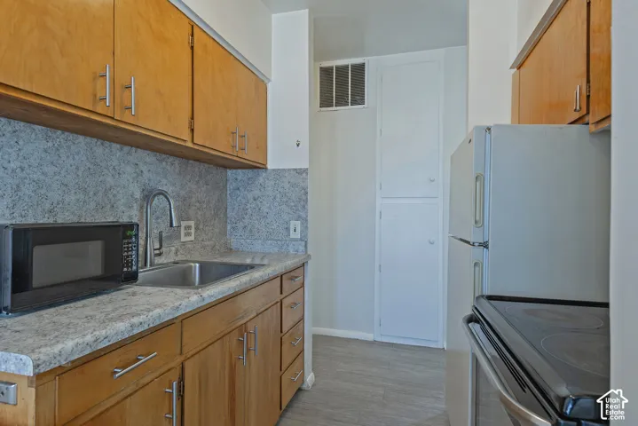Kitchen featuring wood cabinetry, stainless steel sink, granite-style countertops, and a built-in pantry