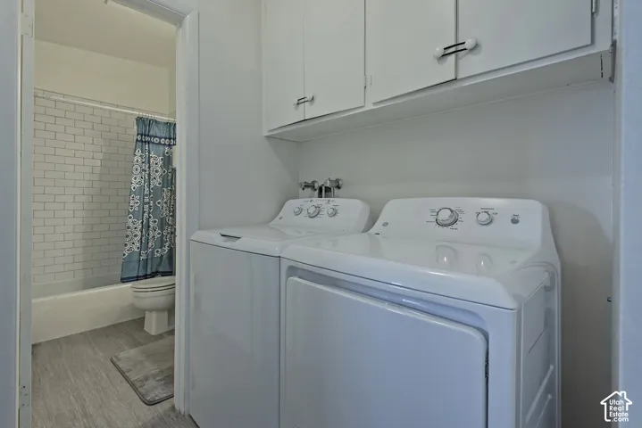 Built-in upper cabinetry, white appliances, and light wood-finish flooring