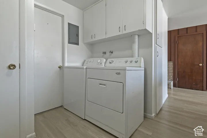 Dedicated laundry area featuring upper cabinetry and wood-finish flooring