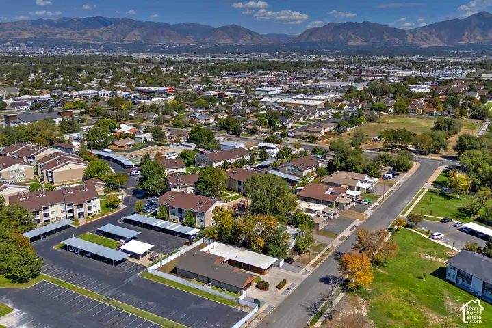 Aerial perspective showcasing multiple residential buildings, paved parking areas with covered spaces, and mature landscaping