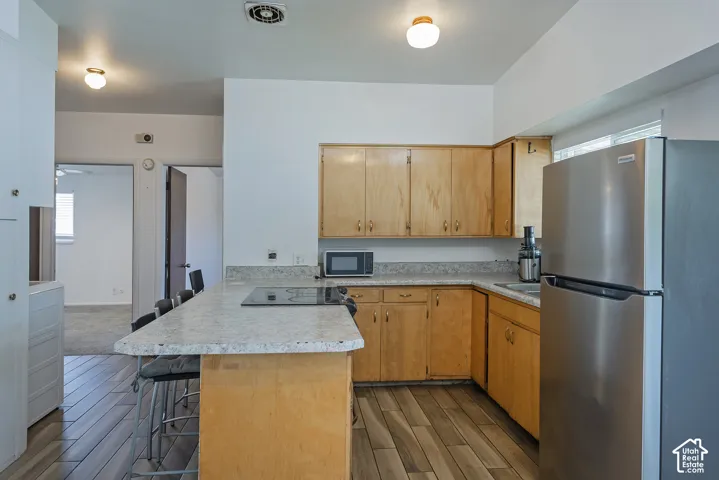 Kitchen featuring wood-finish flooring, light wood cabinetry, stone-finish countertops, and stainless steel appliances