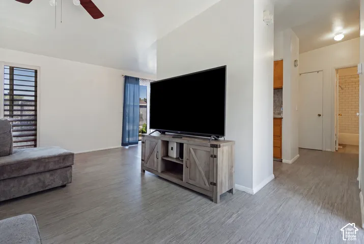 Wood-finish flooring throughout, with a ceiling fan and a window with horizontal blinds