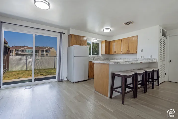 Wood-finish flooring throughout, kitchen with wood cabinetry and light-toned countertops, and sliding glass doors opening to a private outdoor space