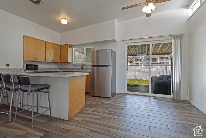 Kitchen with wood cabinetry, light-toned countertops, and stainless steel refrigerator