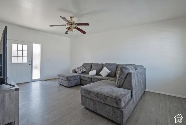 Vaulted ceiling with a ceiling fan, light wood-finish flooring, and a white paneled door with glass inserts